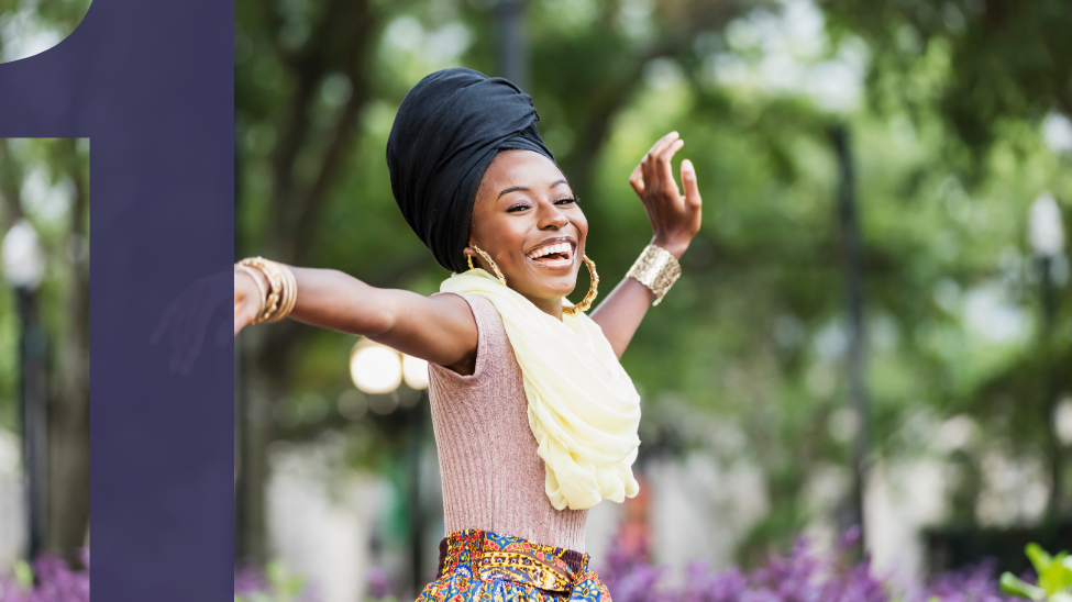 Graceful, young African American woman laughing and dancing outdoors