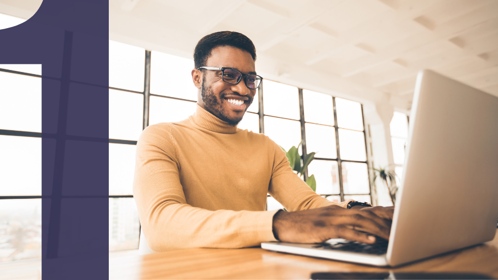 Smiling African American man sitting at laptop computer in a modern office