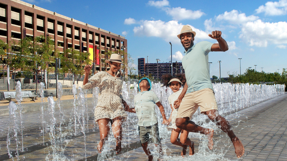 two parents with young children splashing in the fountain on the Detroit RiverWalk
