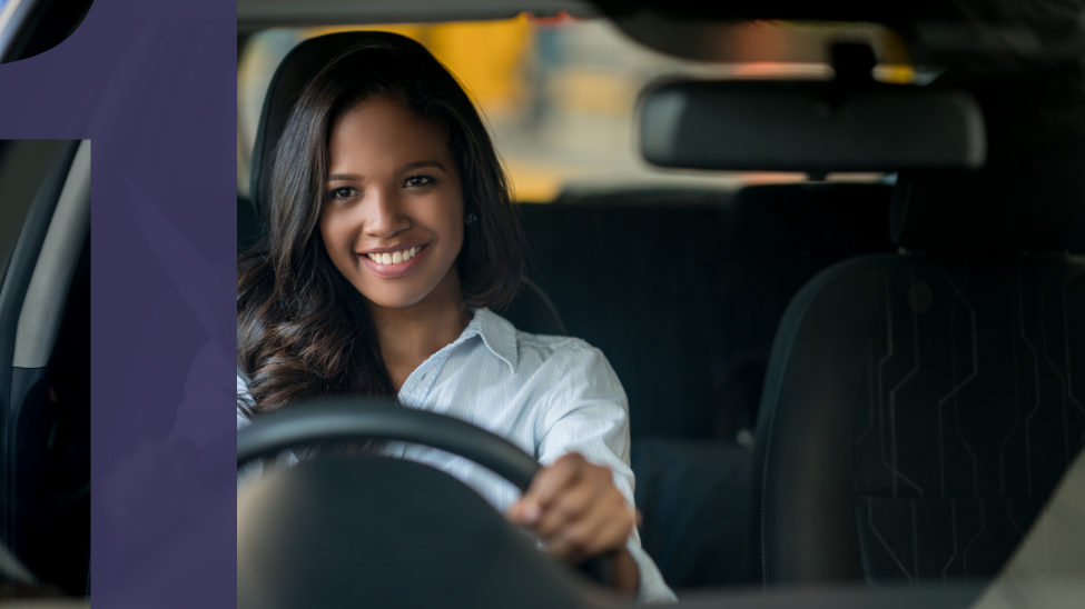 Young black woman sitting in driver's seat of a car smiling