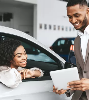 young African American woman buying a car from a professional businessman holding tablet
